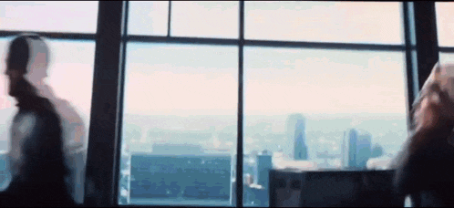 a group of people are standing in front of a large window looking out at the city .