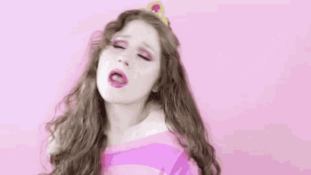 a woman with long hair and a tiara on her head is making a funny face .