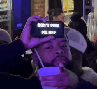 a man holding a cell phone that says do n't piss me off on it