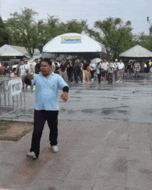 a man in a blue shirt is walking in front of a sign that says ' thailand '
