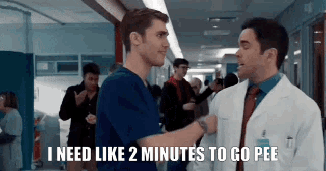 a man in a lab coat is talking to another man in scrubs in a hospital hallway ..