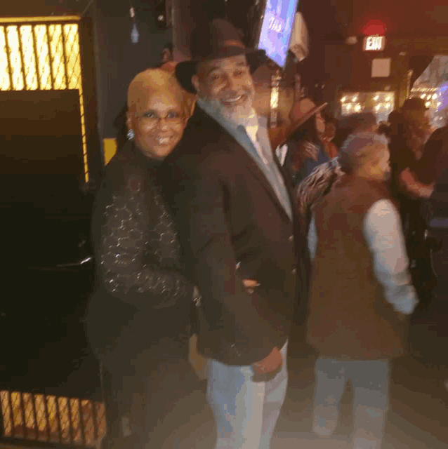 a man and woman are posing for a picture in front of a sign that says exit
