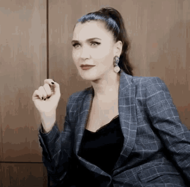 a woman is wearing a plaid jacket and earrings