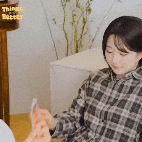 a woman in a plaid shirt is sitting on a couch and holding a card .