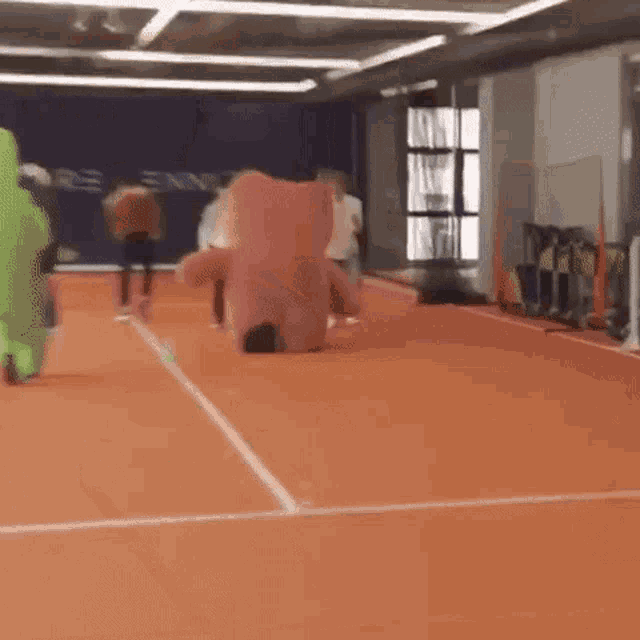 a person in a pink teddy bear costume runs on a tennis court .