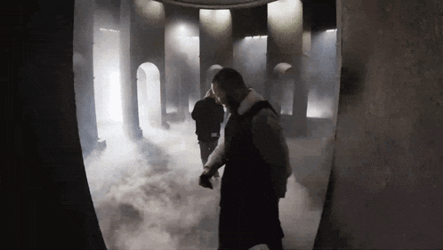 a man is standing in a dark room with smoke coming out of it .