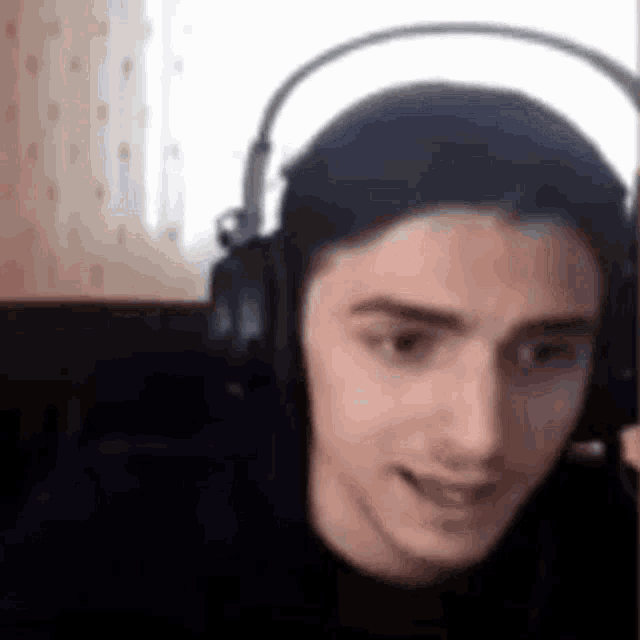 a man wearing headphones is making a funny face and smiling .