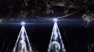 a couple of mannequins are standing next to each other in a dark room with a lot of lights shining on them .