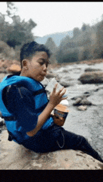 a young boy wearing a life vest drinks from a cup