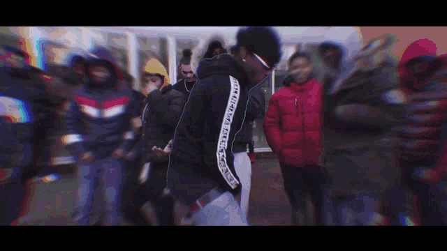 a man wearing a kappa sweatshirt stands in a crowd of people
