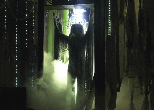 a woman is standing in a dark room with smoke coming out of the doorway