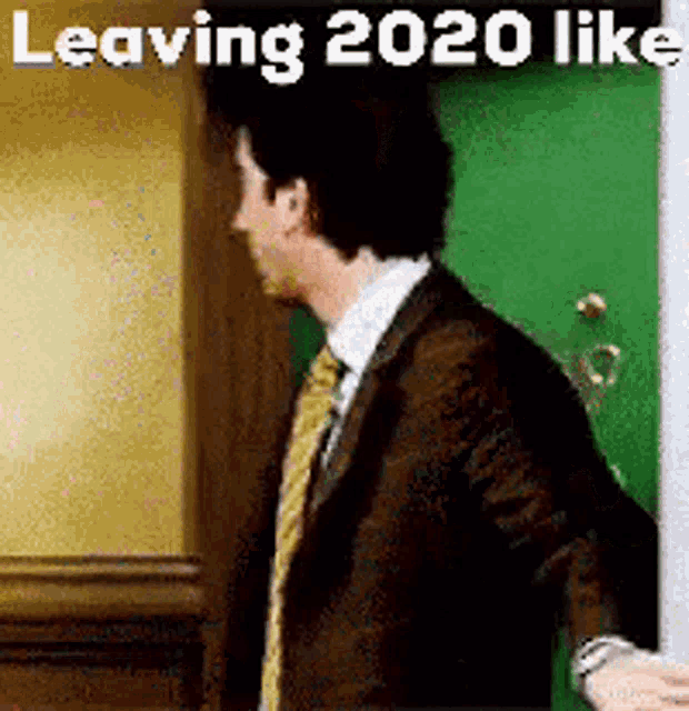 a man in a suit and tie is standing in front of a green door with the caption leaving 2020 like .