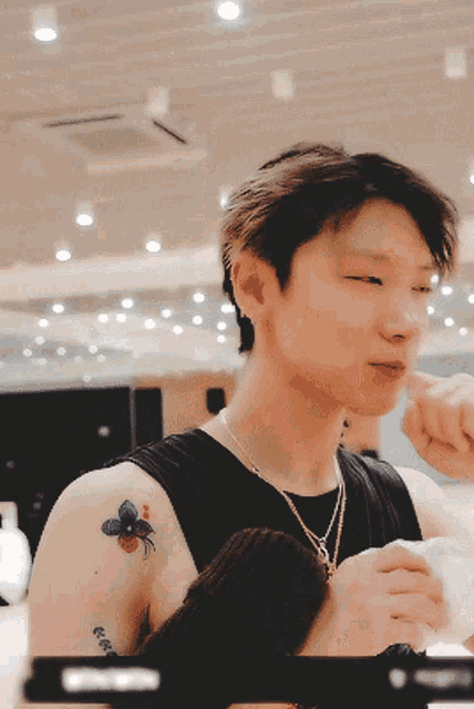 a man with a tattoo of a bee on his shoulder has a necklace around his neck