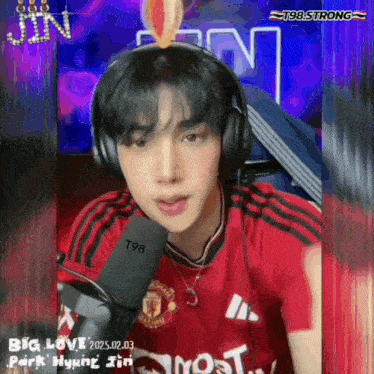 a man wearing headphones and a red manchester united jersey