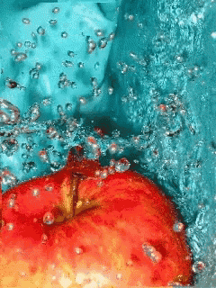 a red apple is being splashed in a pool of water