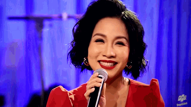 a woman in a red dress is singing into a microphone with the word travelbank on the sleeve