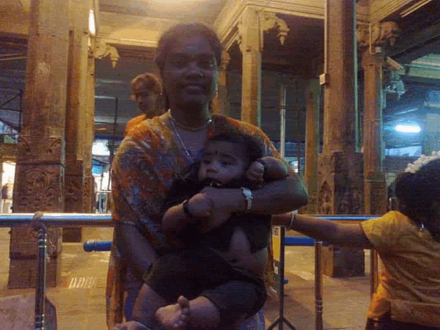 a woman is holding a baby in her arms in a room with columns