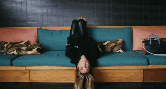 a woman laying upside down on a couch