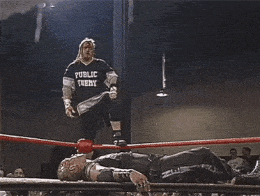 a wrestling match is taking place in a ring with a crowd of people watching .