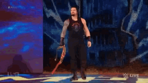 roman reigns is walking down the aisle holding a sword .