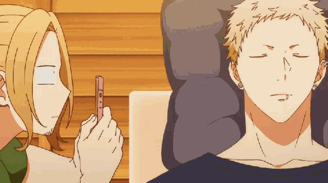 a man is laying on a couch while another man looks at a cell phone