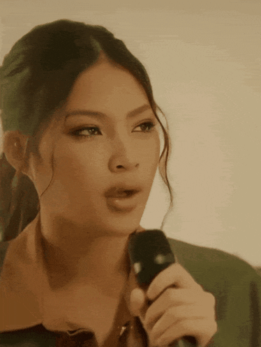 a woman singing into a microphone with a ponytail