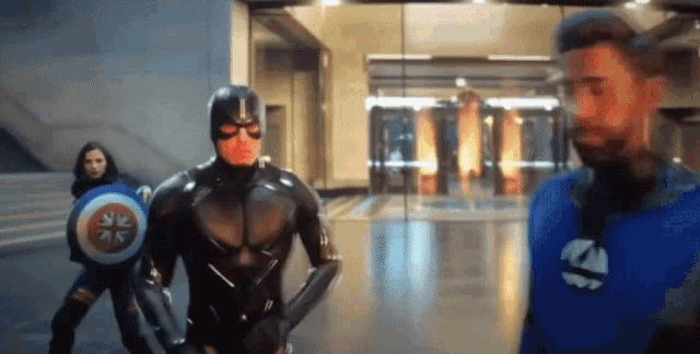a man in a superhero costume stands next to a woman in a superhero costume .