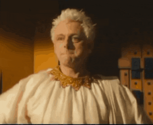 a man with white hair is wearing a white robe and a gold necklace .