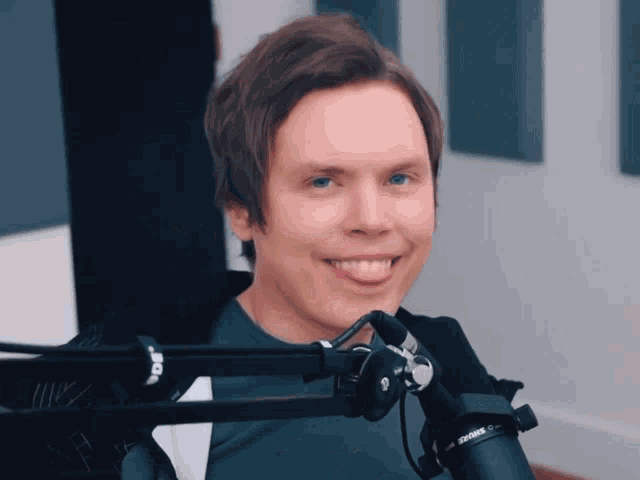 a man in front of a shure microphone smiles
