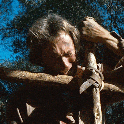 a man is carrying a large wooden stick on his shoulders