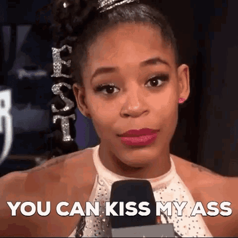 a woman is talking into a microphone with the words " you can kiss my ass " behind her
