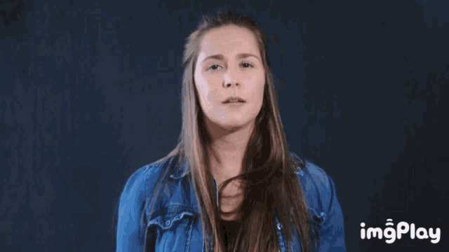 a woman in a denim jacket is making a funny face