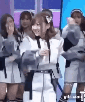 a group of women are standing next to each other on a stage and dancing .