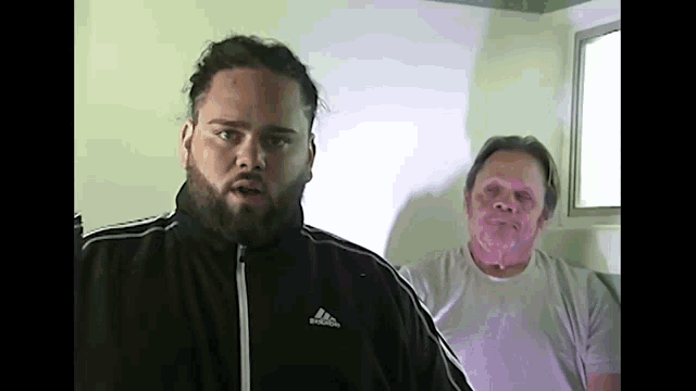 a man wearing a black adidas jacket looks at the camera