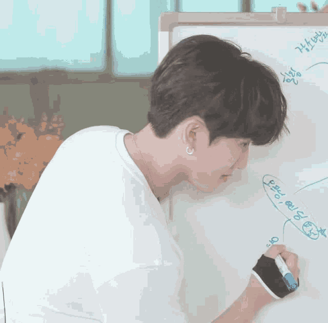 a young man writes on a whiteboard with a marker