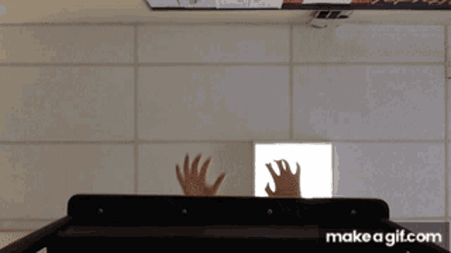 a gif of a person 's hands reaching out from behind a shelf