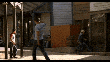 a group of men are walking down a street in front of a building that says ' bakery '
