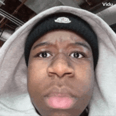 a man wearing a beanie and a hoodie is making a face .