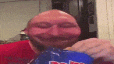 a bald man in a red shirt is eating doritos chips