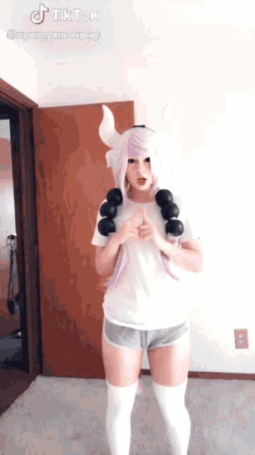 a woman in a white shirt and shorts is standing in front of a door with a tiktok watermark on the bottom