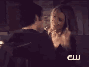a man and woman are kissing in a dark room with the cw logo in the corner