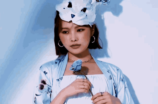 a woman wearing a hat and holding a blue rose
