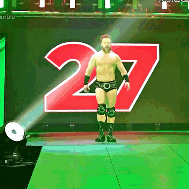a shirtless wrestler stands in front of a large red number 27