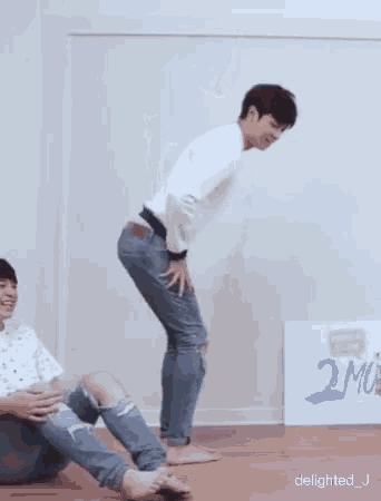 a man in a white sweater and ripped jeans is standing on one leg .