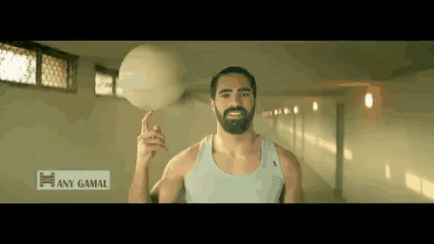 a man with a beard is holding a basketball in his hand and says any gamal in the corner