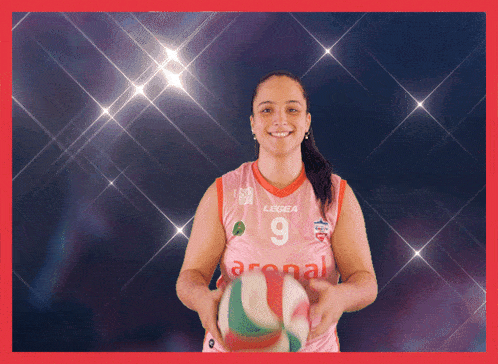 a woman wearing a pink jersey with the number 9 on it holds a volleyball