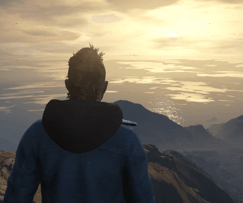 a man in a blue jacket is standing on top of a mountain looking out over a body of water