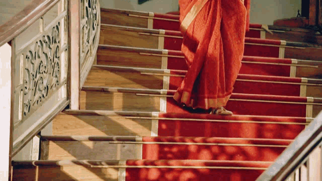 a woman in a red saree walking down a set of stairs