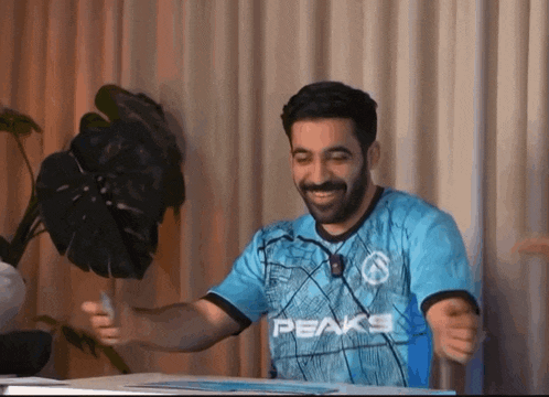 a man wearing a blue peaks shirt is smiling