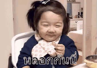 a little girl is sitting in a high chair eating a cookie and making a funny face .